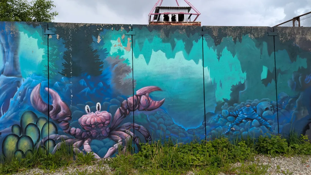 Mural of a large purple crab with big eyes in a teal and blue underwater scene on a metal wall